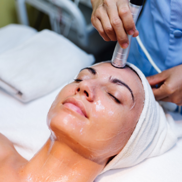 A woman receiving a Hydro Boost facial treatment at Kaya by Reema Salon, showcasing anti-aging and organic peel services.